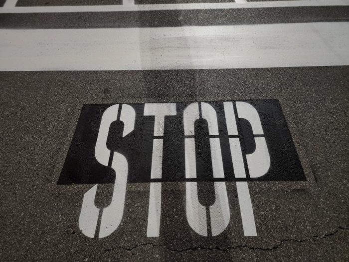 White STOP stencil and stop bar painted on asphalt