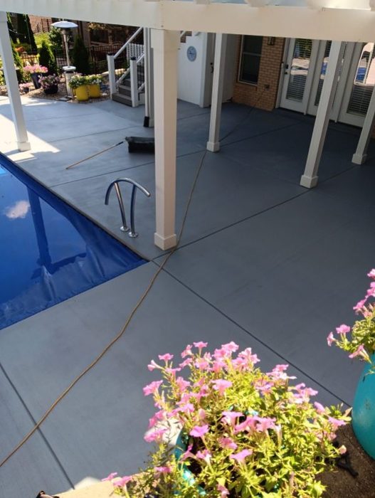 Freshly coated pool deck under a white pergola