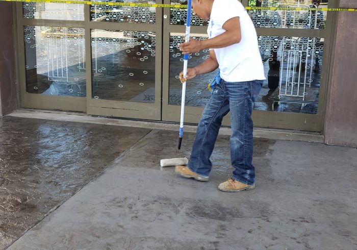 Sealer being rolled onto stamped concrete at a commercial entrance