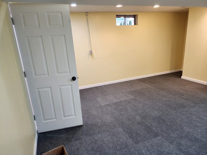 Basement room repainted with pale yellow walls and white baseboards