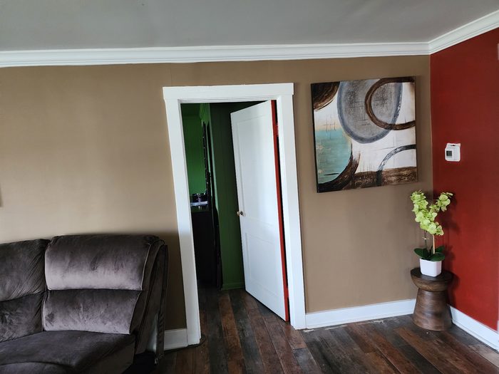 Living room with tan walls, red accent wall and white trim